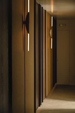 A corridor with wooden paneling and wall-mounted lighting fixtures.
