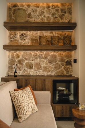 Ein modernes Wohnzimmer mit Steinwand, Holzböden, einem eingebauten Kamin und einer gemütlichen Couch.