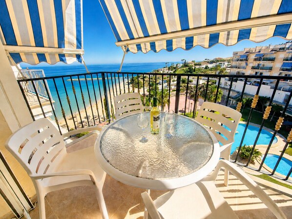 A balcony with a round table, white chairs, and a view of the sea and buildings. - Costa Blanca, Right on the Beach. With private sun terrace, Beautiful resort (El Campello)