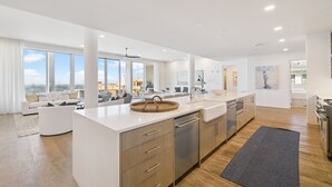 A modern kitchen with a large island, stainless steel appliances, and a view to the outside.