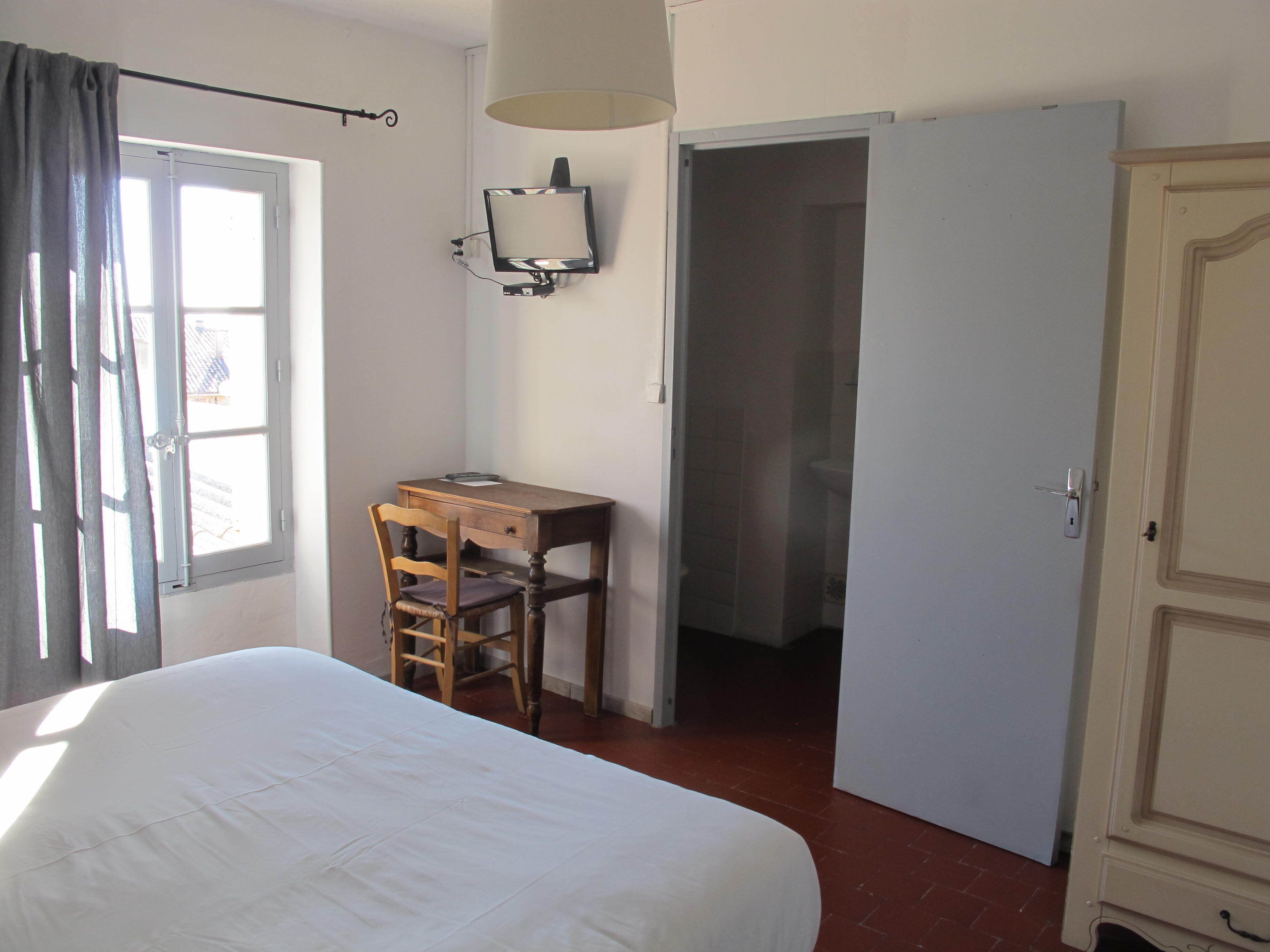 Un dormitorio con cama, un escritorio con silla, televisor y armario.