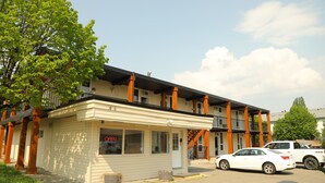 A two-story building with a beige exterior and orange columns. There is a white car parked in front.