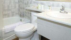 A bathroom with a bathtub, toilet, sink, and a large mirror.