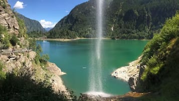 Un paysage naturel comprenant une cascade, un lac et des montagnes boisées.