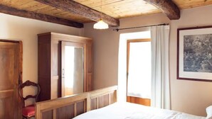 Une chambre à coucher avec un lit en bois, une chaise, une armoire et une fenêtre avec des rideaux.