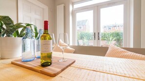 Ein Holztisch mit einer Weinflasche, einem Glas und zwei leeren Flaschen auf einem Tablett.