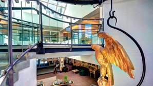 Ein mehrgeschossiges Atrium mit einer großen Skulptur eines goldenen Adlers, Glasgeländern und einem modernen Innenarchitektur-Design.