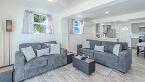 Un salon moderne avec deux canapés gris, une table basse et un ventilateur de plafond.