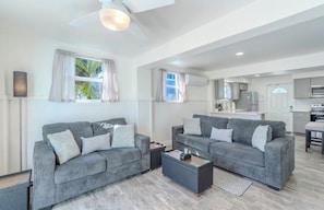 A modern living room with two grey sofas, a coffee table, and a ceiling fan.