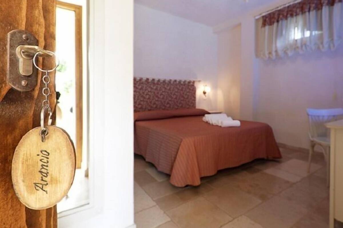 Une chambre à coucher comprenant un lit, une table de chevet, une chaise et un luminaire suspendu.