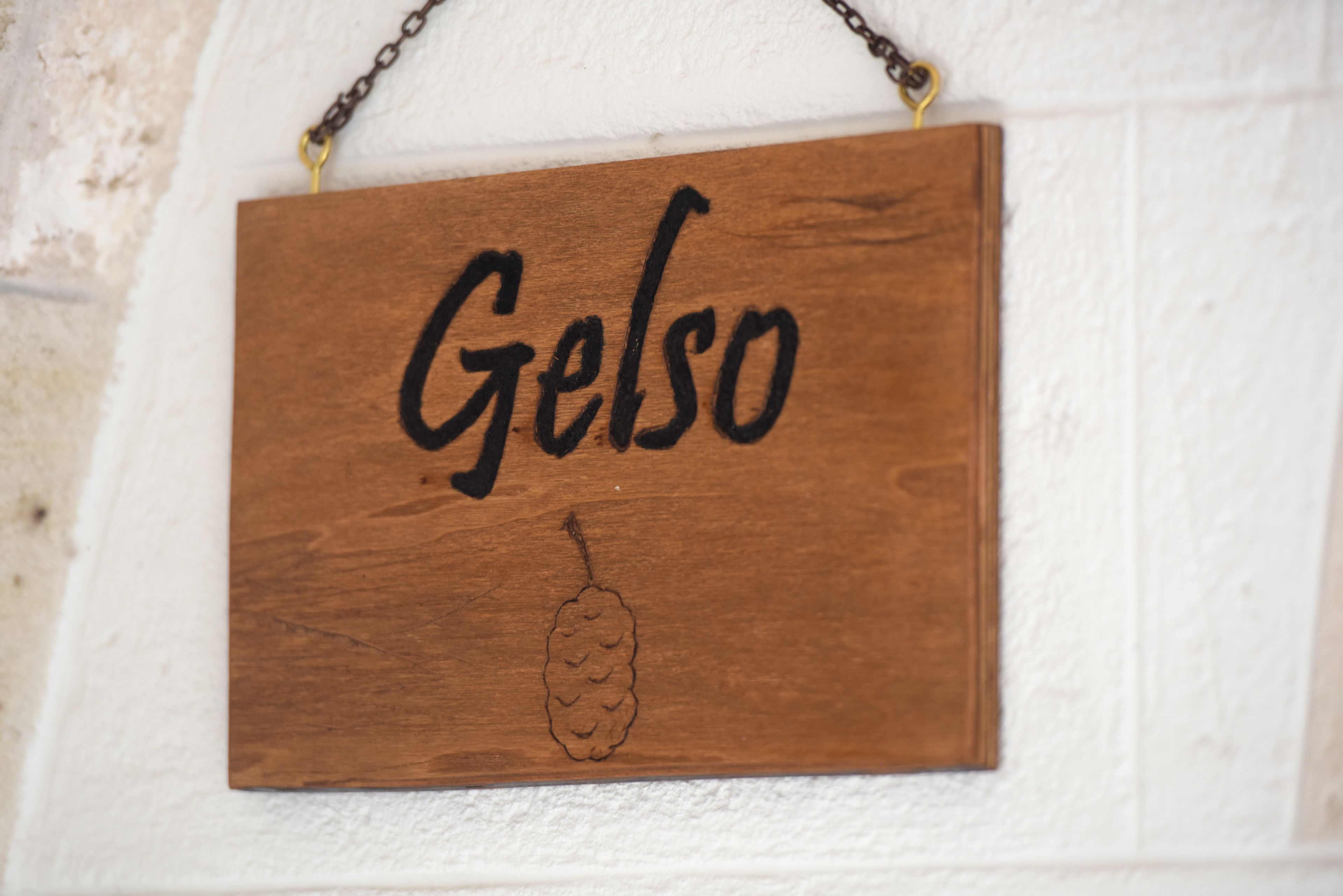 Un letrero de madera con el nombre 'Gelso' y un símbolo de piña.