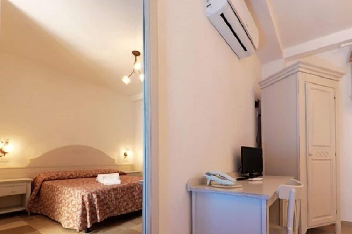 Une chambre comprenant un lit, un bureau, une chaise, un appareil de climatisation et une armoire.
