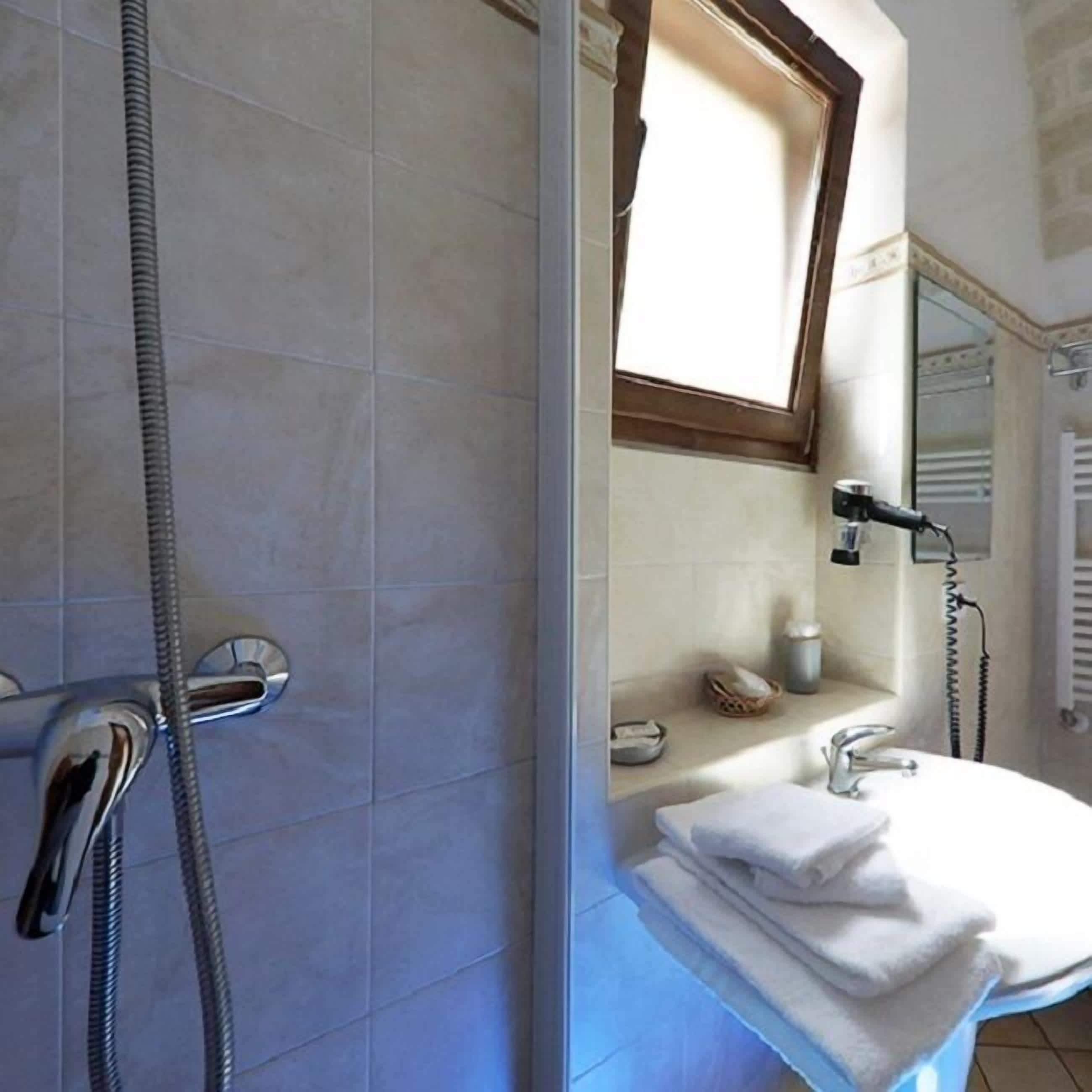 A bathroom with a shower, a sink, a mirror, and a towel rack.
