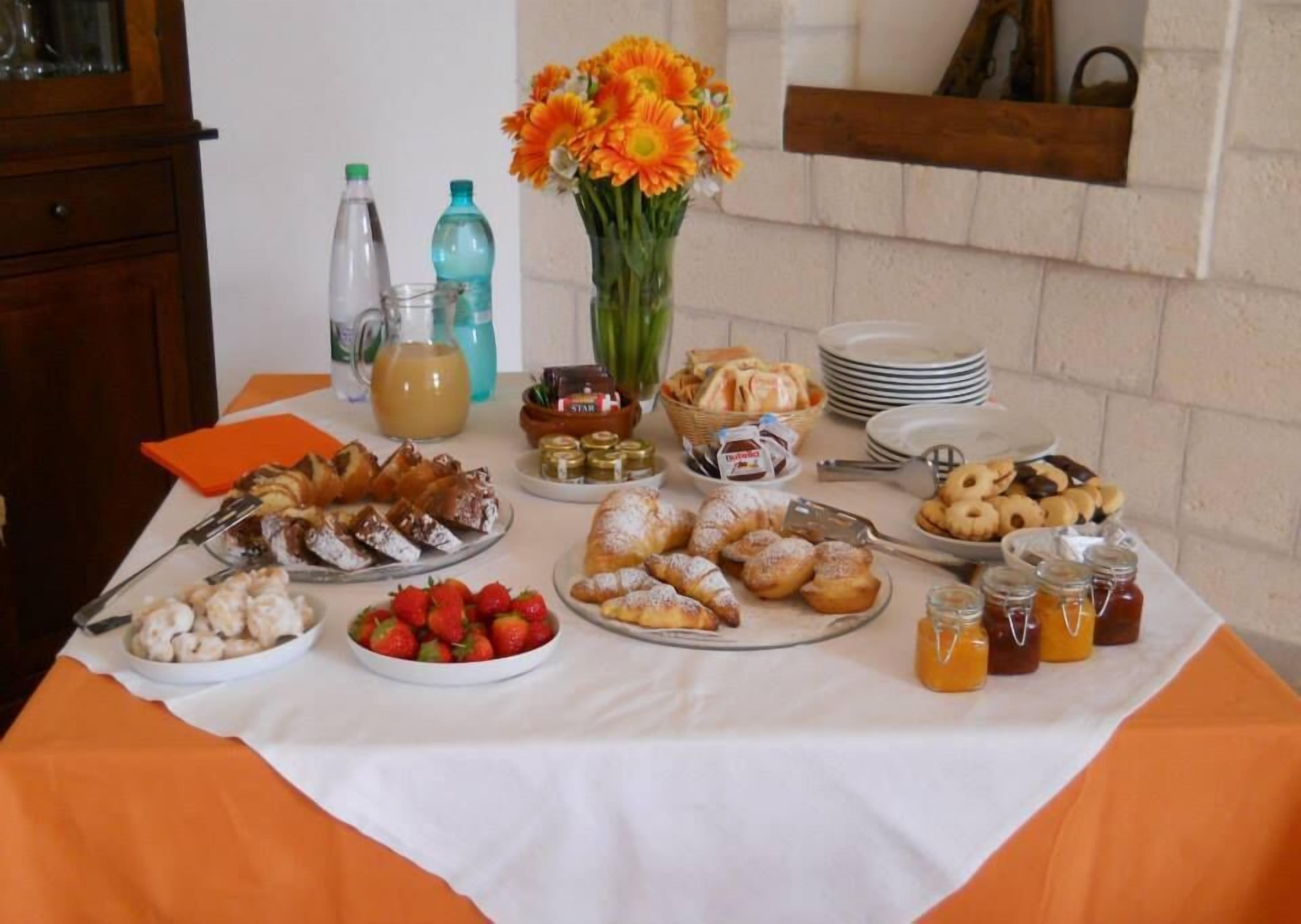 A buffet table with various food items, including pastries, fruits, and condiments.
