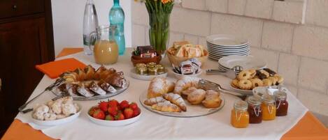 A buffet table with various food items, including pastries, fruits, and condiments.