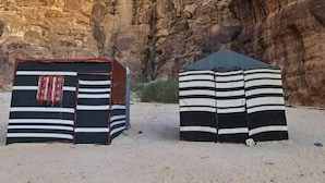 Un canyon étroit, avec des formations rocheuses, et deux tentes rayées au premier plan.