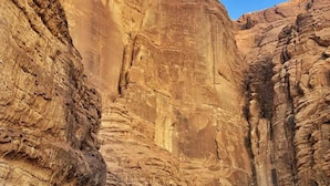 Un paysage désertique avec une grande formation rocheuse et plusieurs tentes.
