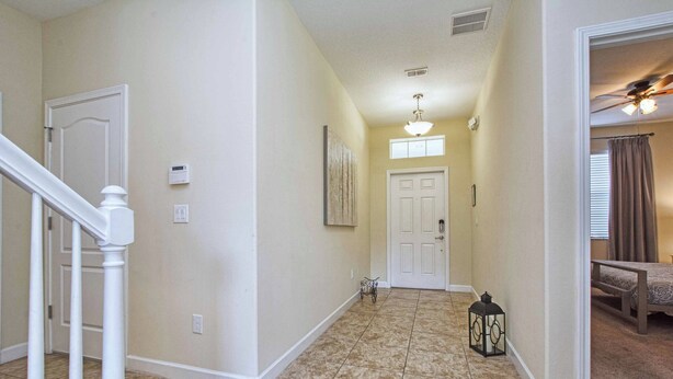 A hallway with a white door, a small decorative cart, and a lantern on the floor. - 5BR Disney Pool Home | 3 King Bedrooms | Private Pool, Spa & BBQ | Sleeps 13 (Kissimmee)