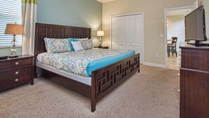 A bedroom with a bed, nightstands, a dresser, a television, and a closet. - 5BR Disney Pool Home | 3 King Bedrooms | Private Pool, Spa & BBQ | Sleeps 13 (Kissimmee)