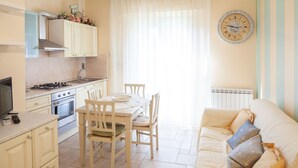 Une cuisine compacte comprenant un coin repas, un canapé et une horloge murale.