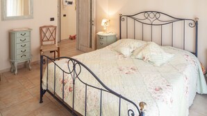 Une chambre à coucher comprenant un lit, une table de chevet, une commode, une chaise et un miroir.