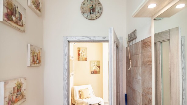Un couloir avec un lit, une horloge et des œuvres d’art accrochées aux murs.