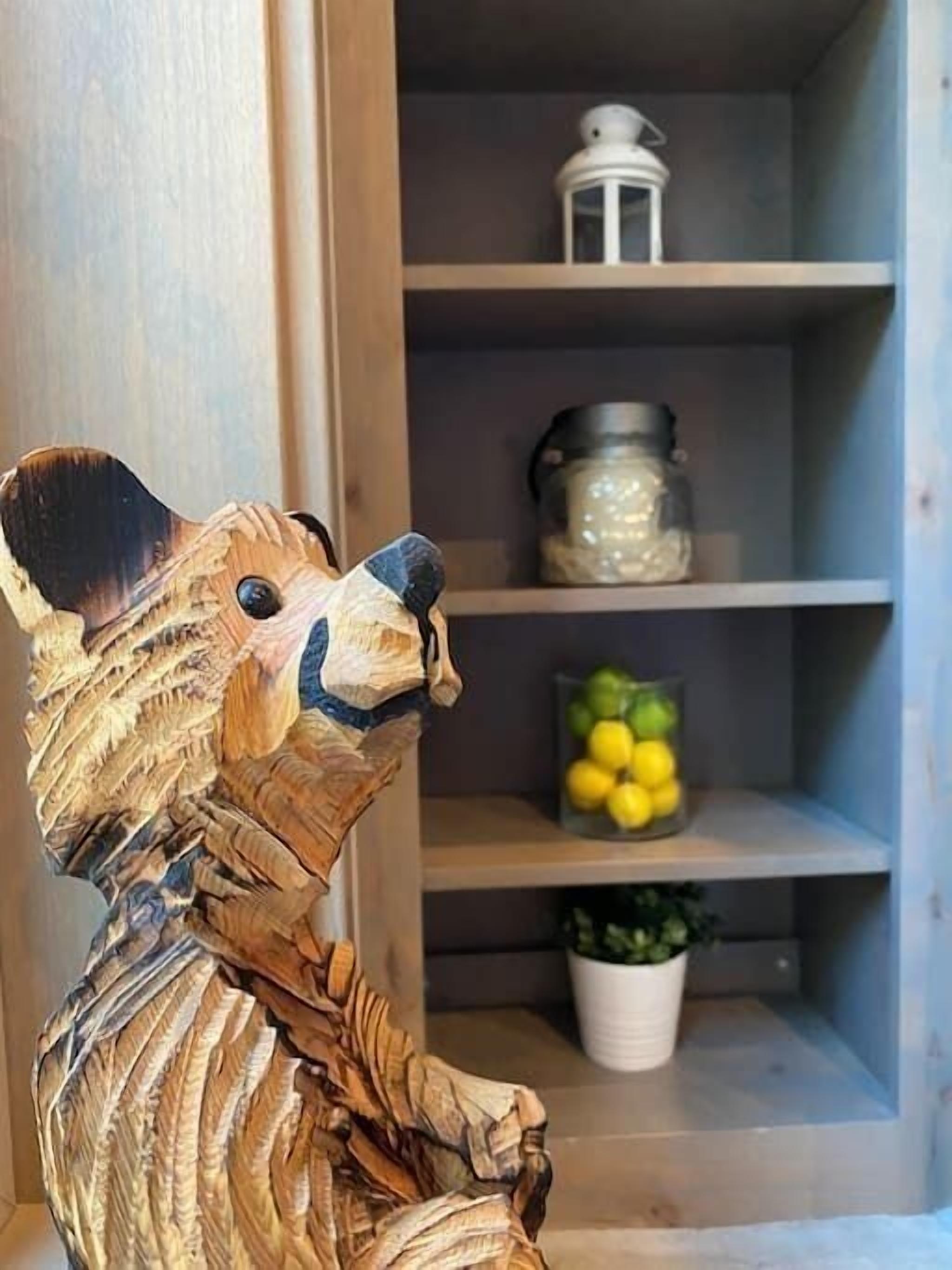 En träskulptur som föreställer en mus, placerad i ett rum med hyllor fyllda med olika föremål.