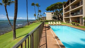 Ein Hotel mit Pool, Palmen und Meerblick.