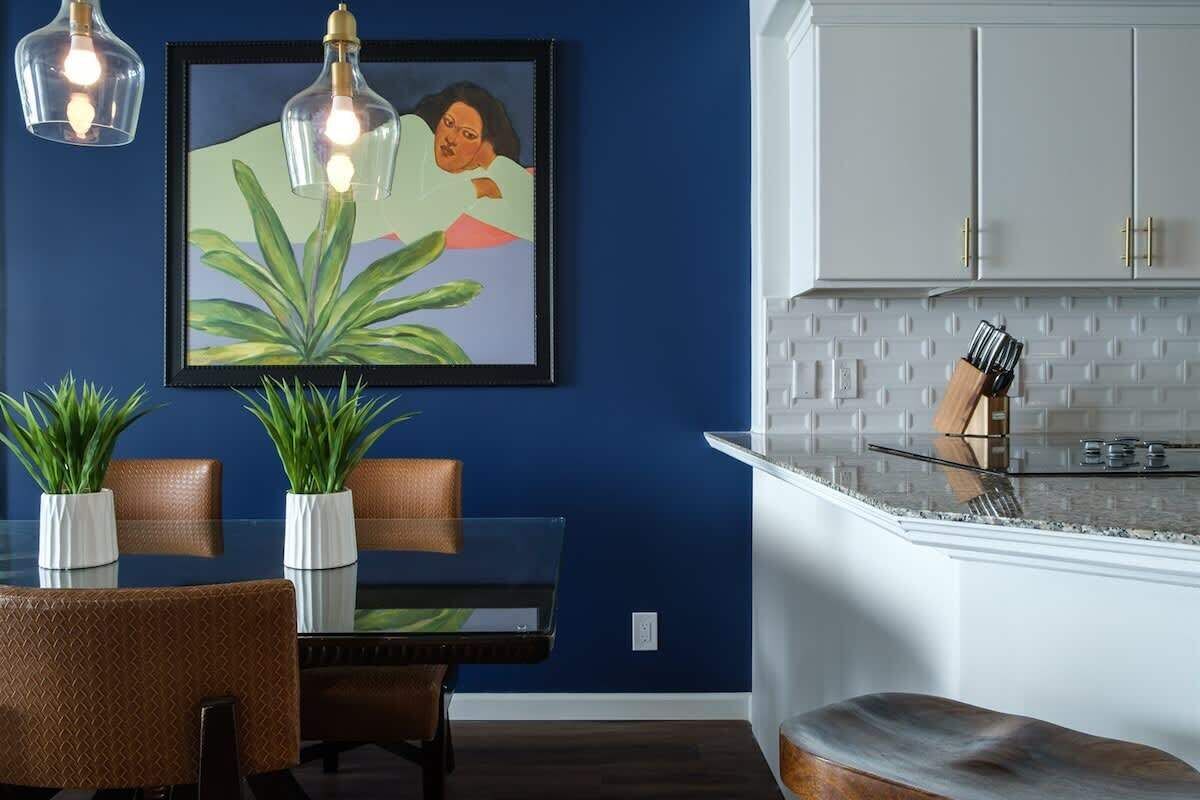 A dining area with a glass table, chairs, and potted plants.