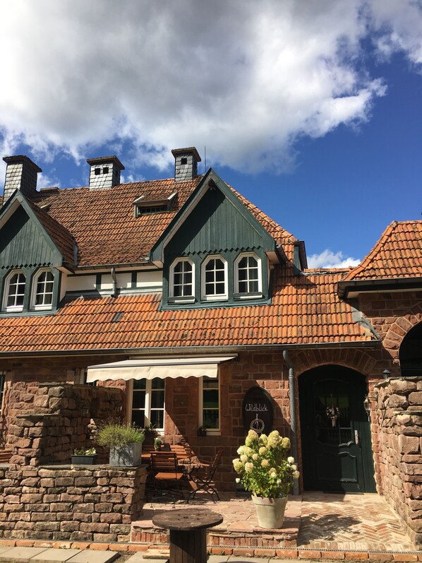 A traditional building with a tiled roof, stone walls, and a green door. - Vacation apartment "Wildblick" - Stylish living in a historic ambience  (Mürlenbach)