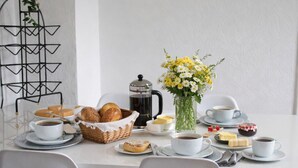 Ein Frühstückstisch mit Kaffeekanne, Gebäck und einer Blumenvase.
