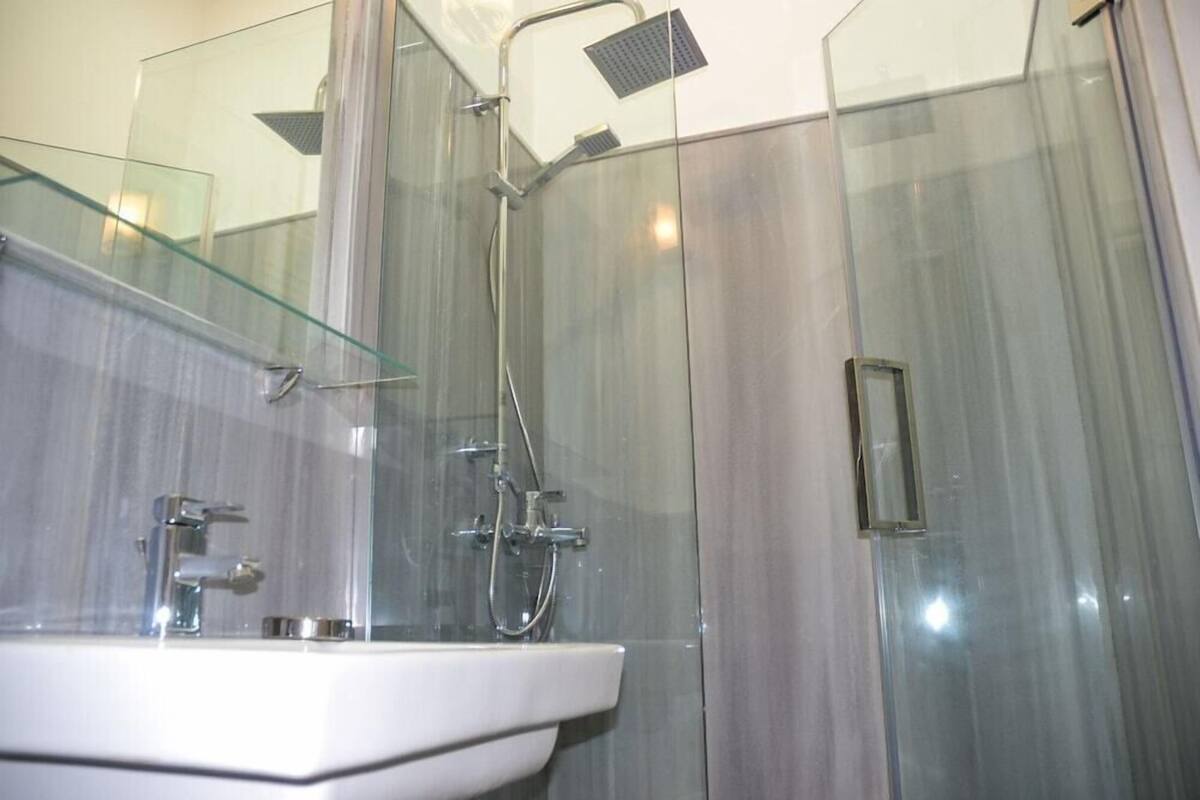 A modern bathroom with a glass shower enclosure, a white sink, and a glass partition.