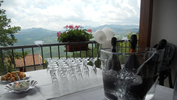 Une table dressée avec des verres à vin et une bouteille de vin, avec une vue panoramique sur les montagnes en arrière-plan.