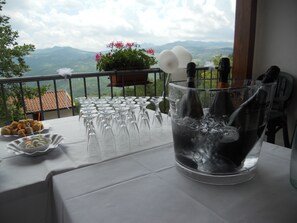 Une table dressée avec des verres à vin et une bouteille de vin, avec une vue panoramique sur les montagnes en arrière-plan.