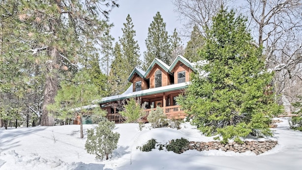A log cabin with a wrap-around porch, surrounded by snow and trees. - Near Bear Valley: Peaceful Arnold Home w/ Hot Tub (Arnold)