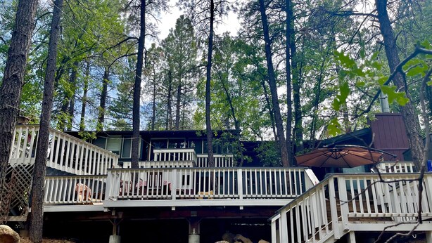 Une cabane dotée d’une terrasse en bois et d’un escalier menant à une zone abritée.