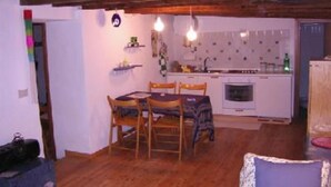 A compact kitchen with white cabinets, a sink, and a stove. There is a dining area with a table and chairs.