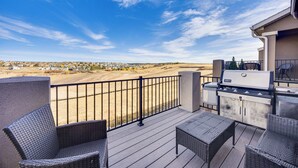 A balcony with wicker furniture, a grill, and a view of a distant town. - 8 Mi to USAFA! Townhome w/ Game Room & Backyard (Colorado Springs)