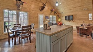 A wooden cabin interior with a dining area, kitchen, and living space. - Peaceful Family Cabin on 10 Acres w/ Game Room! (Heflin)