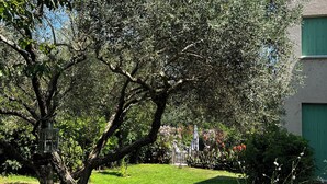 A tree-lined garden with a wooden bench, a bird feeder, and a building with green shutters. - Villa with private pool, large enclosed garden, beaches 25mn away,10 pers (Castries)