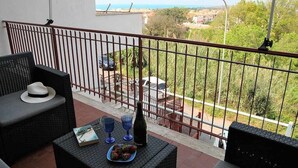 A balcony with wicker furniture, a bottle, and a book.