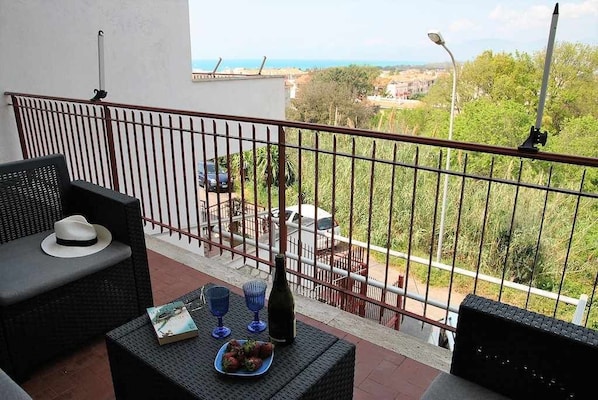 A balcony with wicker furniture, a bottle, and a book.