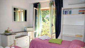 A bedroom with two beds, a bedside table, a mirror, and a window with curtains.