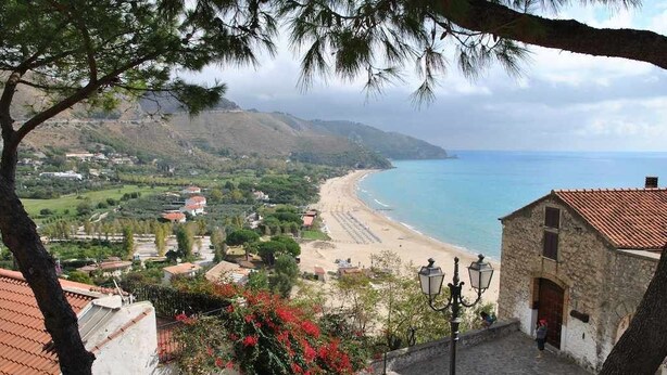 A coastal town with a beach, stone buildings, and a view of the sea.