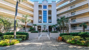 Un hotel de varios pisos con un atrio central, balcones y un patio ajardinado.