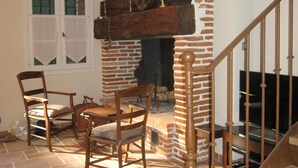 A living room with a brick fireplace, wooden furniture, and a staircase.