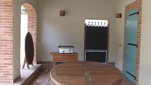 A patio with a wooden table, a brick wall, and a blue door.