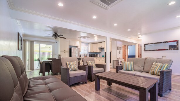 A spacious living room with a brown leather sofa, two wicker armchairs, and a wooden coffee table. A ceiling fan and recessed lighting are visible. - Suncrest House near beautiful Trinity Alps Wilderness Area (Junction City)