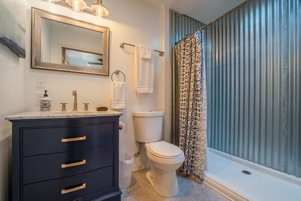 A bathroom with a black vanity, a white toilet, and a shower with patterned curtains.