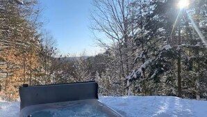 Un jacuzzi en un entorno nevado al aire libre, con cielo despejado.